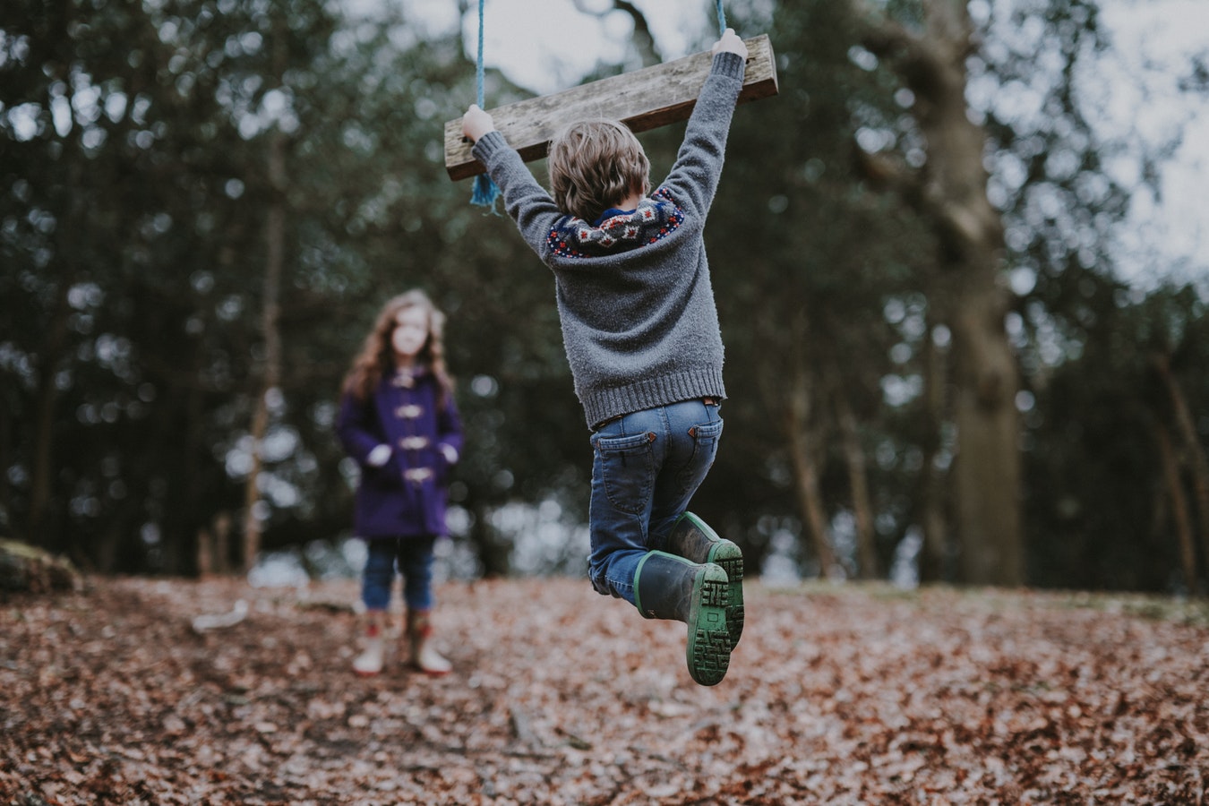 Kinder schaukeln im Herbst